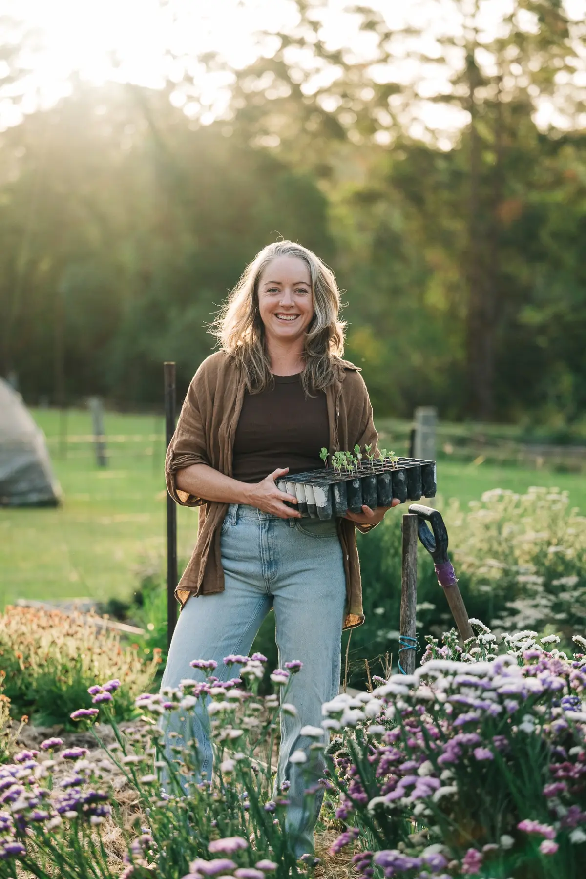 Ambre Whatley holding a tray of seedlings in her flower garden